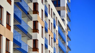 Şık yüzlü ve geniş pencereli modern konut binası. Büyüyen bir mahallede çağdaş şehir mimarisi. Güneşli bir gökyüzünün altında gayrimenkul gelişimi.