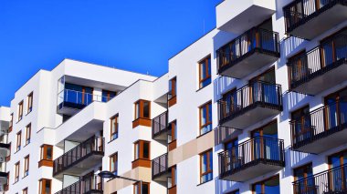 Şık yüzlü ve geniş pencereli modern konut binası. Büyüyen bir mahallede çağdaş şehir mimarisi. Güneşli bir gökyüzünün altında gayrimenkul gelişimi.