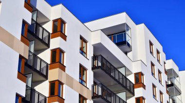 Şık yüzlü ve geniş pencereli modern konut binası. Büyüyen bir mahallede çağdaş şehir mimarisi. Güneşli bir gökyüzünün altında gayrimenkul gelişimi.