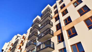 Şık yüzlü ve geniş pencereli modern konut binası. Büyüyen bir mahallede çağdaş şehir mimarisi. Güneşli bir gökyüzünün altında gayrimenkul gelişimi.