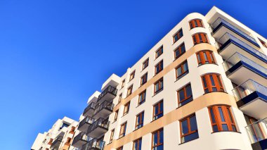 Şık yüzlü ve geniş pencereli modern konut binası. Büyüyen bir mahallede çağdaş şehir mimarisi. Güneşli bir gökyüzünün altında gayrimenkul gelişimi.