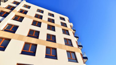 Şık yüzlü ve geniş pencereli modern konut binası. Büyüyen bir mahallede çağdaş şehir mimarisi. Güneşli bir gökyüzünün altında gayrimenkul gelişimi.