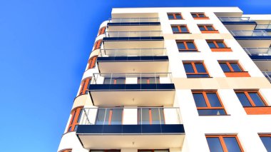 Şık yüzlü ve geniş pencereli modern konut binası. Büyüyen bir mahallede çağdaş şehir mimarisi. Güneşli bir gökyüzünün altında gayrimenkul gelişimi.