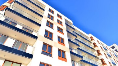 Şık yüzlü ve geniş pencereli modern konut binası. Büyüyen bir mahallede çağdaş şehir mimarisi. Güneşli bir gökyüzünün altında gayrimenkul gelişimi.