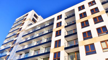 Şık yüzlü ve geniş pencereli modern konut binası. Büyüyen bir mahallede çağdaş şehir mimarisi. Güneşli bir gökyüzünün altında gayrimenkul gelişimi.