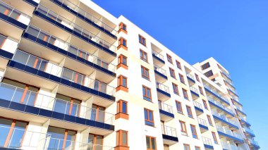 Şık yüzlü ve geniş pencereli modern konut binası. Büyüyen bir mahallede çağdaş şehir mimarisi. Güneşli bir gökyüzünün altında gayrimenkul gelişimi.