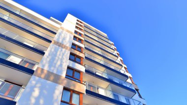 Şık yüzlü ve geniş pencereli modern konut binası. Büyüyen bir mahallede çağdaş şehir mimarisi. Güneşli bir gökyüzünün altında gayrimenkul gelişimi.