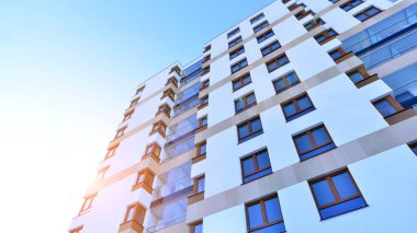 Şık yüzlü ve geniş pencereli modern konut binası. Büyüyen bir mahallede çağdaş şehir mimarisi. Güneşli bir gökyüzünün altında gayrimenkul gelişimi.