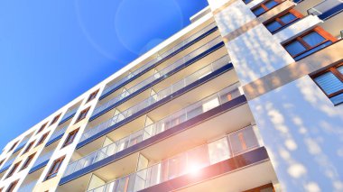 Şık yüzlü ve geniş pencereli modern konut binası. Büyüyen bir mahallede çağdaş şehir mimarisi. Güneşli bir gökyüzünün altında gayrimenkul gelişimi.