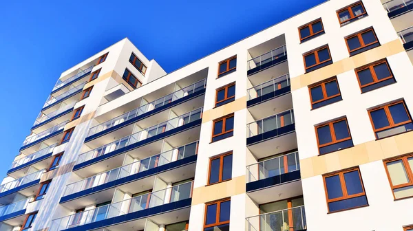 Şık yüzlü ve geniş pencereli modern konut binası. Büyüyen bir mahallede çağdaş şehir mimarisi. Güneşli bir gökyüzünün altında gayrimenkul gelişimi.