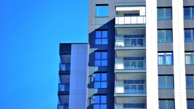 Çok katlı, modern bir apartmanın dış cephesi, pencereleri ve balkonları..