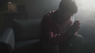 Umutsuz bir adamın silueti gece tek başına dua ederken ilahi ışık huzmeleri sessizce pencereden içeri süzülüyor..