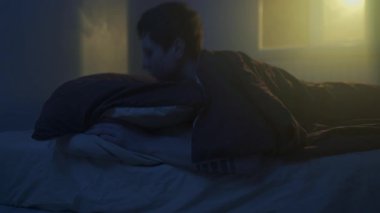 Genç adam geceleri karanlık bir yatak odasında uyuyamıyor. Huzursuzluk ve uykusuzluk havası, yakın çekim yaşam tarzı.