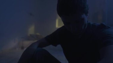 Üzgün bunalımlı adam karanlık yatak odasında yalnız oturuyor, duygusal çöküntü, umutsuz ruh hali ve yalnızlık..