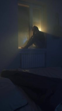 Üzgün bunalımlı adam karanlık yatak odasında yalnız oturuyor, duygusal çöküntü, umutsuz ruh hali ve yalnızlık..