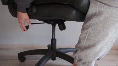 Ofis sandalyesinde oturan ve yüksekliği manivela ile ayarlayan kişi rahat bir konum bulmak için, günlük yaşam tarzı anı.