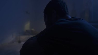 Üzgün bunalımlı adam karanlık yatak odasında yalnız oturuyor, duygusal çöküntü, umutsuz ruh hali ve yalnızlık.