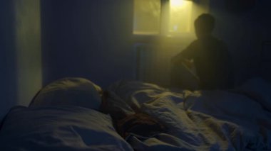 Kalbi kırık bir adam karanlık bir odada yatakta oturuyor, ayrılık, üzüntü ve yalnızlıkla boğuşuyor..