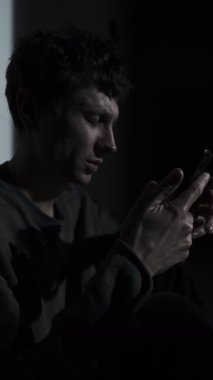 Karanlıkta tek başına oturan bir adam, telefonunda ayrılık mesajı okuyor. Duygusal acı, yalnızlık, şok ve ilişki çevrimiçi bitiyor..