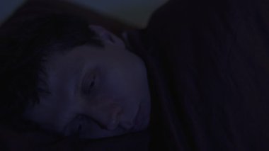 Geceleri, gözleri açık, karanlığa doğru bakan bir adamın yakın çekimi. Uykusuzluk, endişe, stres, aşırı düşünme ve uykusuz gece havası..