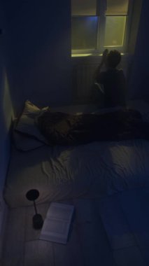 Umutsuz bir adamın silueti gece tek başına dua ederken ilahi ışık huzmeleri sessizce pencereden içeri süzülüyor..