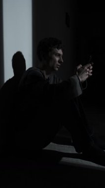 Karanlıkta tek başına oturan bir adam, telefonunda ayrılık mesajı okuyor. Duygusal acı, yalnızlık, şok ve ilişki çevrimiçi bitiyor..