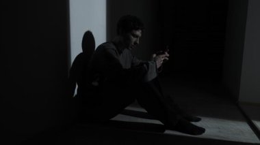 Karanlıkta tek başına oturan bir adam, telefonunda ayrılık mesajı okuyor. Duygusal acı, yalnızlık, şok ve ilişki çevrimiçi bitiyor..