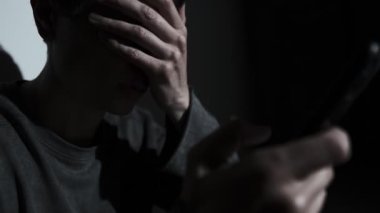Karanlıkta tek başına oturan bir adam, telefonunda ayrılık mesajı okuyor. Duygusal acı, yalnızlık, şok ve ilişki çevrimiçi bitiyor..
