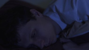 Geceleri uyuyamayan, yorgun ve boş gözlerle karanlığa bakan yalnız bir adamın yakın çekimi. Üzüntü, duygusal çöküntü ve ümitsiz düşünceler.