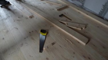 Yeni bir iç mekanda tadilat sırasında bitmemiş zeminde el testeresi ve ahşap parçaları vardı. Gerçek inşaat ve DIY marangozluk atmosferi.