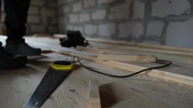 Ahşap zemin kurulumu, kereste kesmeden önce el testeresi alan işçiler. DIY inşaatı yakın plan.