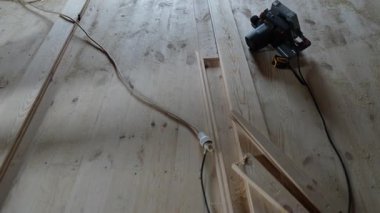 Zemin kurulumu sırasında kamera ahşap tahta ve aletlerin üzerinden kayıyor. Elektrikli testere ve işe hazır malzemelerle otantik gerçek yaşam inşa ortamı.