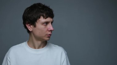 Sakin bir adam kafasını yavaşça çevirir ve düşünceli bir tarafsız ifadeyle bir şeyi gözlemler ve değerlendirir. Dikkatli analiz ve karar verme kavramı.