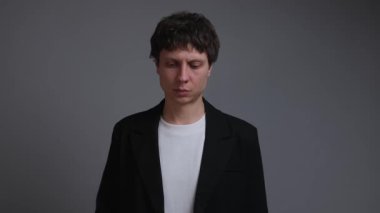 Adam sessiz baskı altında başını sallar, rahatsızlığa rağmen kabul etmeye çalışır.