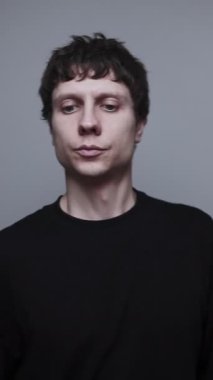 Hayalet telefon erişiminde dikkat bozukluğu ve huzursuz odaklanma. Tarafsız gri arka planda boş bir ele bakan genç adam