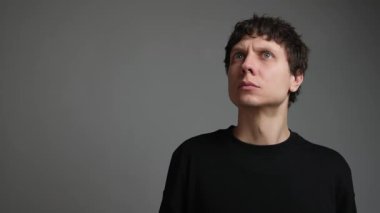 Siyahlı bir gencin hayali bir telefon çalmasını can kulağıyla dinleyen portresini yakından çek. Telefon bağımlılığı, dijital anksiyete ve tarafsız arkaplanda bilgilendirme stresi kavramı.