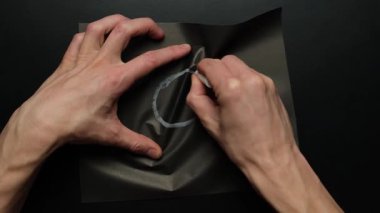 Elle gösterilen duygusal durum siyah kağıda çizilmiş üzgün yüz buruşuyor ve stres patlamasının bir sembolü olarak atılıyor.