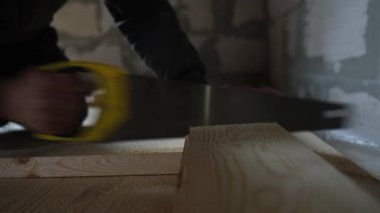 Yerdeki döşeme montajı sırasında tahta kesen bir işçinin yakın çekimi. Gerçek elle inşa süreci