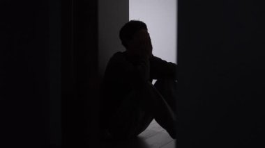 Gerçek hayatta erkek duygusal çöküntüsü, erkeklerin zihinsel aşırı yüklenme yalnız siluet yoluyla gösteriliyor. Karanlık koridorda ellerinde yüzler, stres birikimi ve psikolojik baskı ile oturuyor..