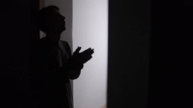 Adam duygusal olarak aşırı yüklenmeden sonra kapıyı kapatıyor, siluet kapıda duruyor, elleri yüzün üzerinde duruyor, izolasyonu seçiyor, stresten uzaklaşıyor ve temastan kaçınıyor..