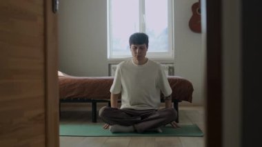 Milenyum adamı, dövmeleri evde, yatak odasında meditasyon yapıyor. Farkındalık alıştırması yapıyor. Gündüz hayatı yaşıyor.