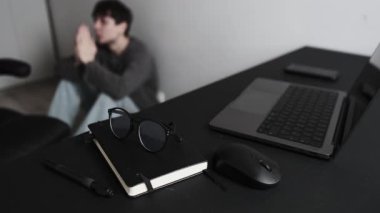 İş yerinde dua eden adam, odak noktası olan masa ve umut ve destek arayan bulanık işçi..