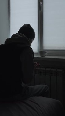 Evde ısıtma yok, adam soğuk dairede radyatörün yanında ellerini ısıtıyor, enerji krizi yaşam tarzı.