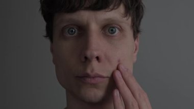 Genç adamın yüzüne, sivilcelerine, sivilcelerine ve cilt kusurlarına, erkek derilerine, gerçek hayata dokunuşuna yakından bakın.