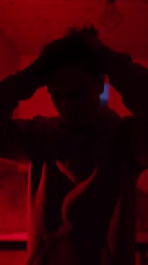 Kırmızı ışıkta uyuşturucu yoksunluğu çeken bir adam, yakın plan psikolojik acı, bağımlılık mücadelesi, zihinsel çöküntü ve evde kontrol kaybı gösteren bir siluet.