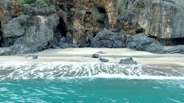 Plano aéreo mirando olas rocas y cuevas en frente del océano — Vídeos de Stock