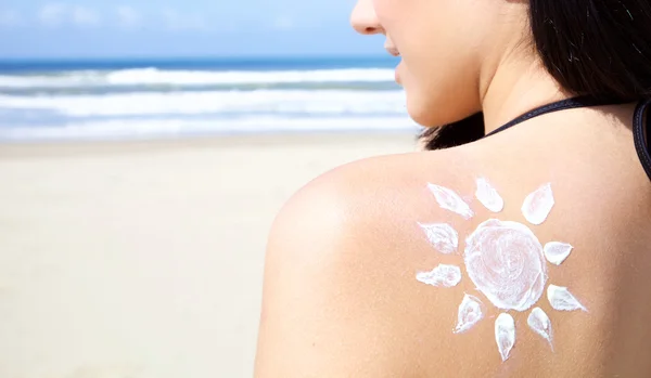 Carino giovane donna sorridente sulla spiaggia in bikini con sole dipinto con crema sul retro primo piano — Foto Stock