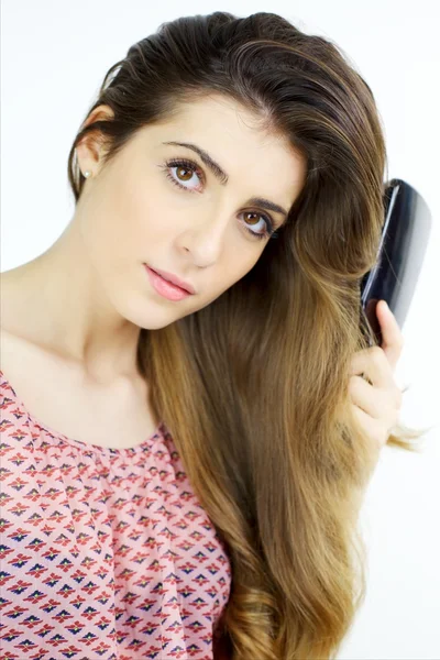 Beautiful girl brushing long wavy silky blonde hair — Stock Photo, Image