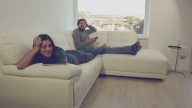 Erkek ve kadın kullanarak konuşmak koltukta yalan hücre telefon ve tablet 4 k