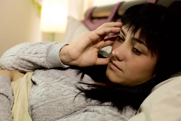 Mujer triste en la cama con fuerte dolor de cabeza —  Fotos de Stock